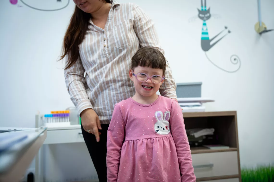 A girl stands in front of her mom in Tatiana's ambulatory.