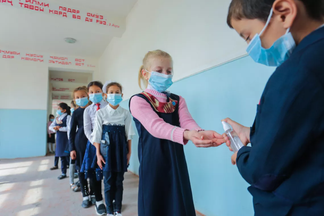 Teacher applying disinfectant to kids