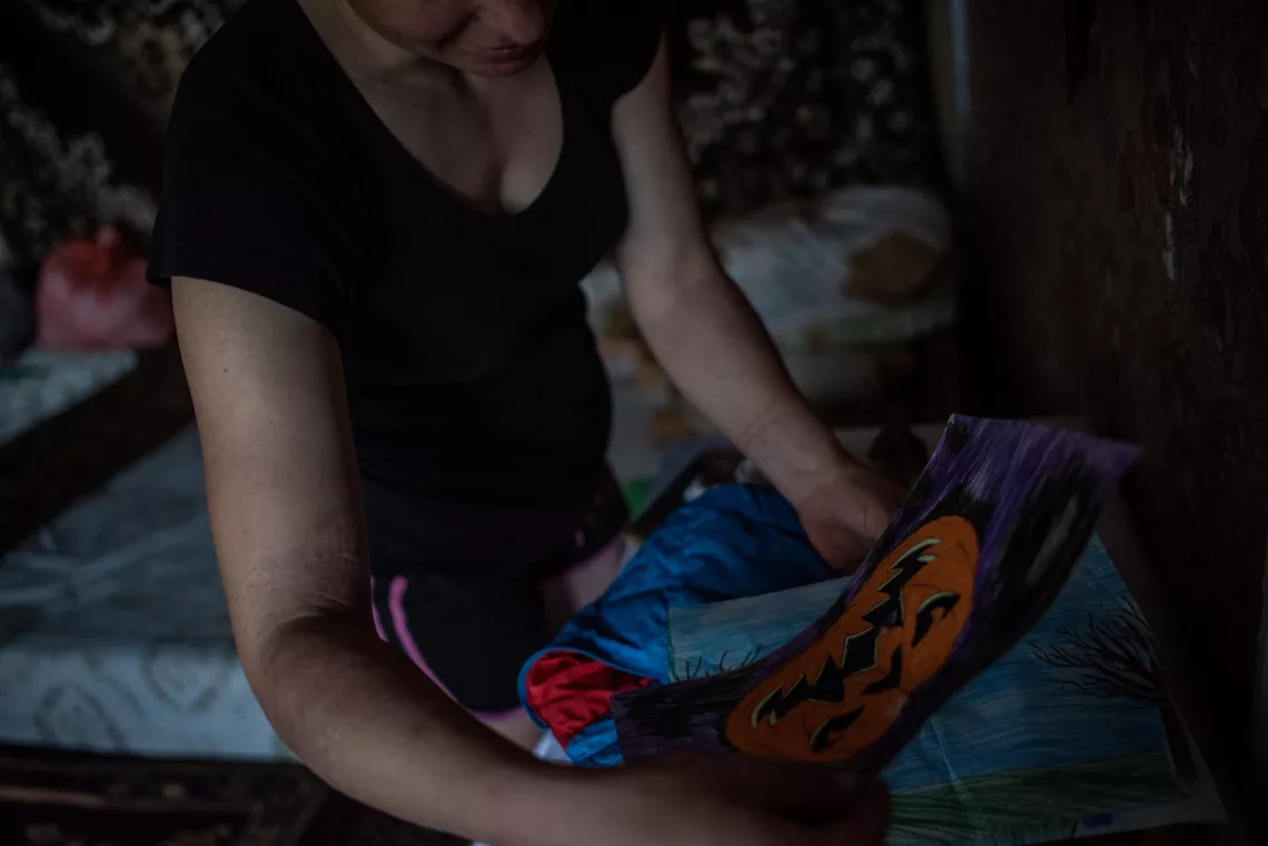 Silvia looks at a picture drawn by youngest daughter Lillia* at their home in Moldova.