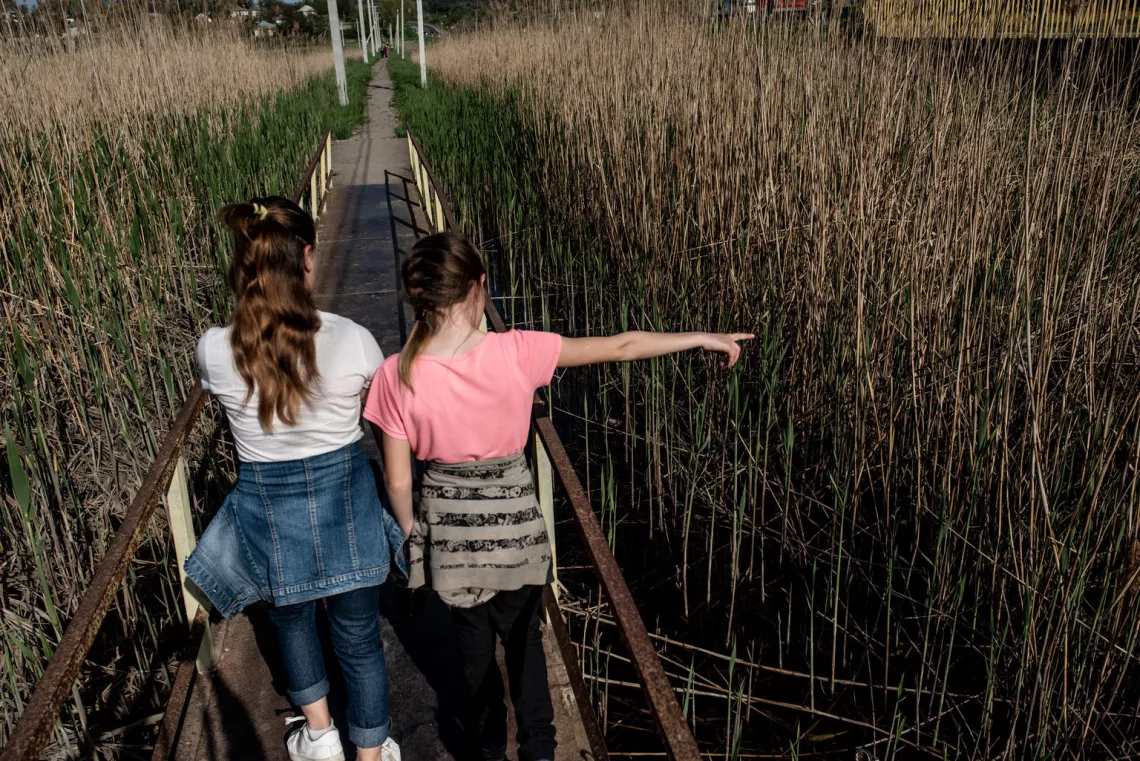 Liza and her younger sister Lillia walk outside together close to their home.
