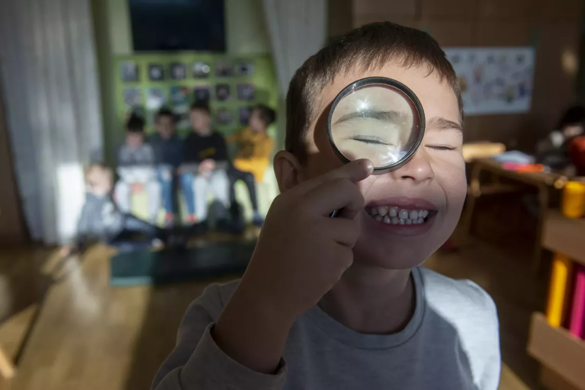A child looks through a magnifying glass in an inclusive kindergarten in Belgrade, Serbia