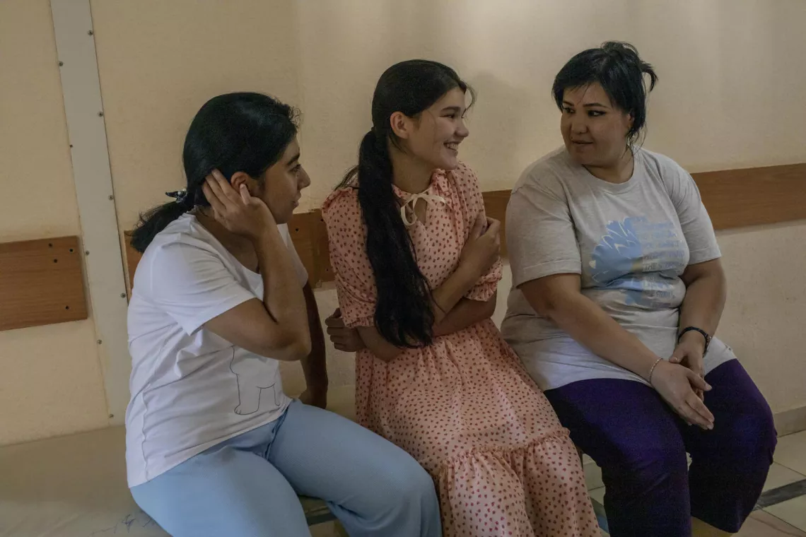 A girl holds her arm and laughs with family after receiving an HPV vaccine. 