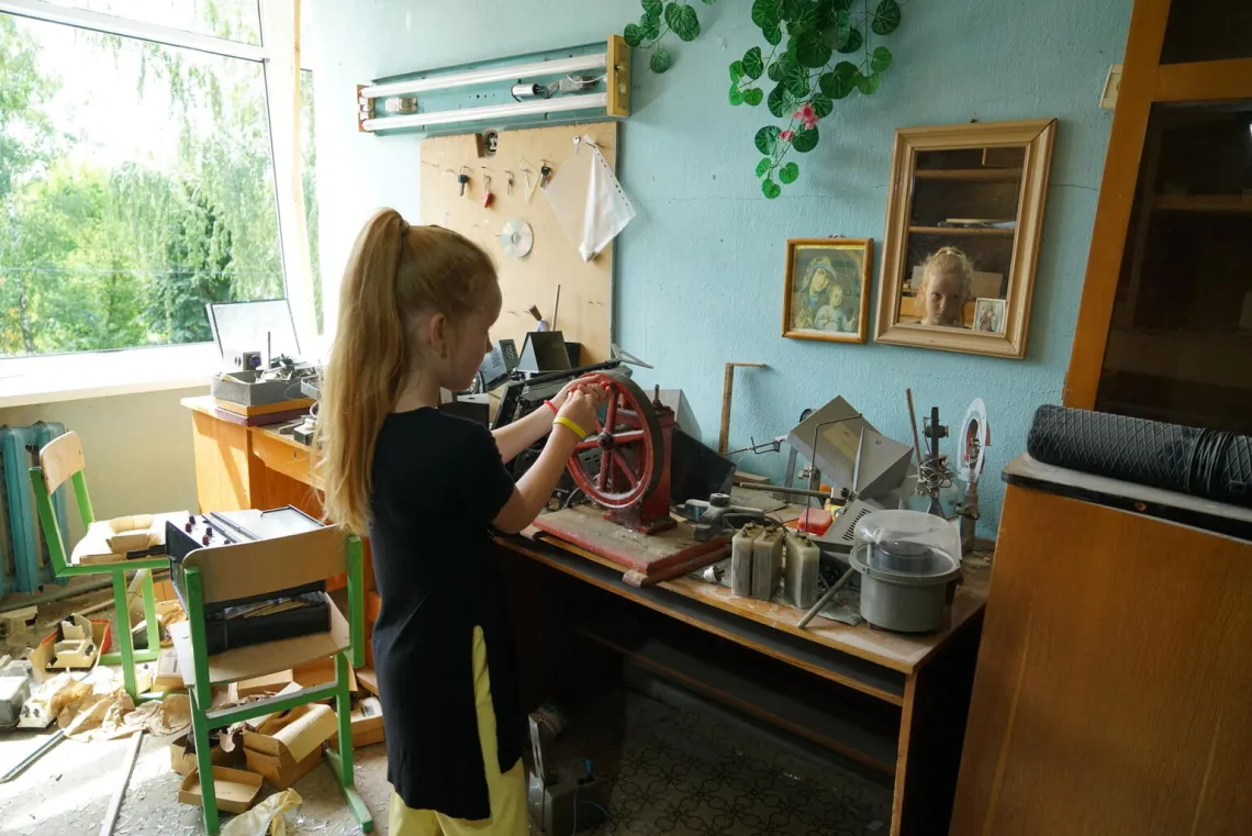 8-year-old Anya stands in a classroom at her damaged school in Buzova, Ukraine.