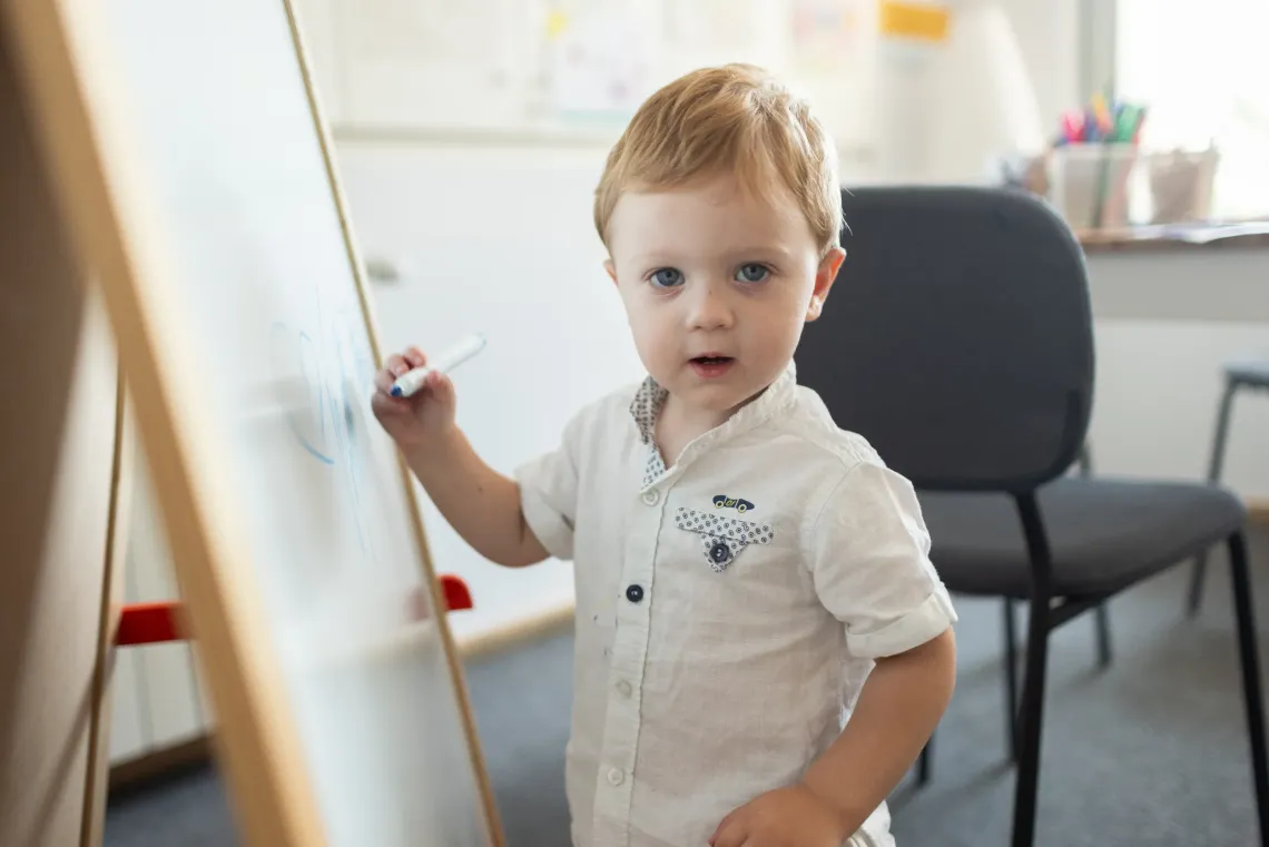 Fedir, 1 year old, is testing his creative skills on a drawing board at the Child Friendly Space in Romania.