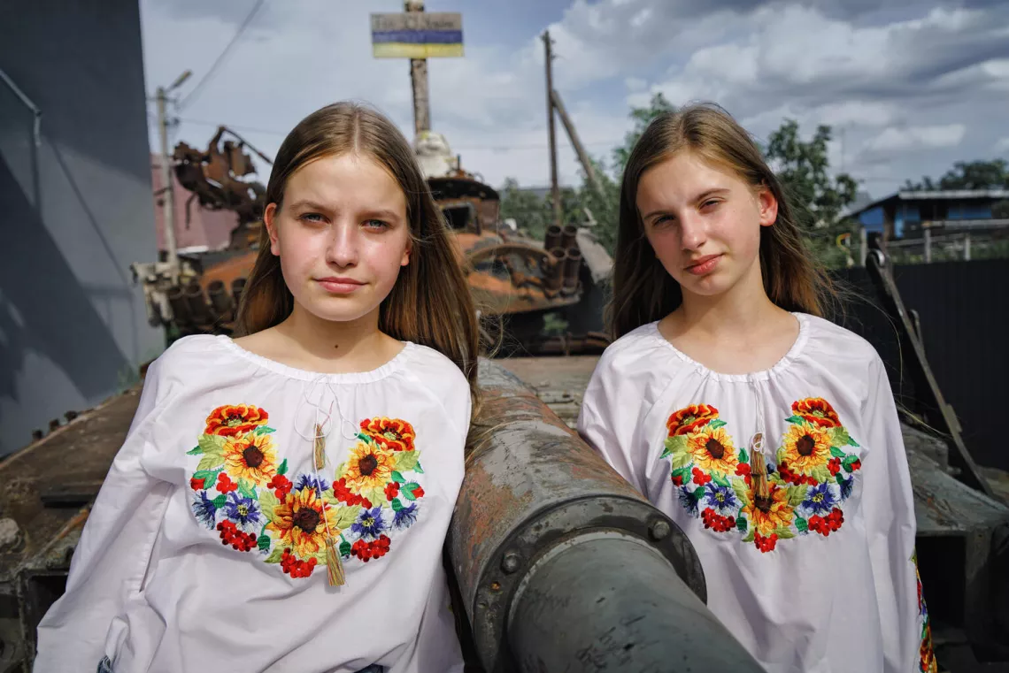 14-year-old Nelya and her 13-year-old sister Lilya are standing, dressed in colourful vyshyvankas.