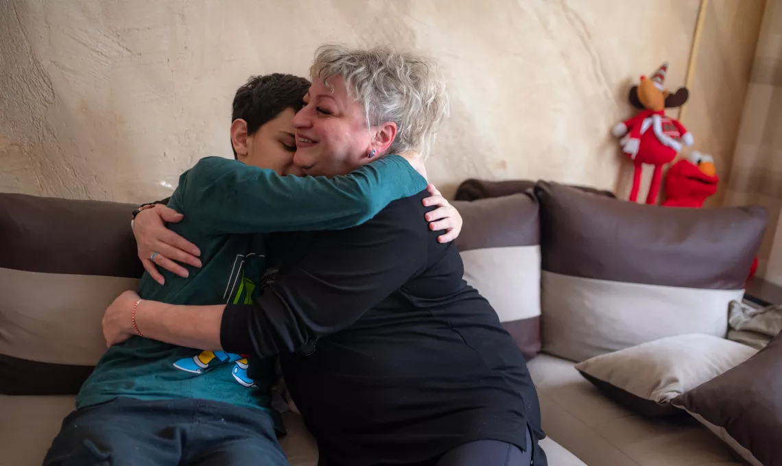 A foster mother and a child embrace. 