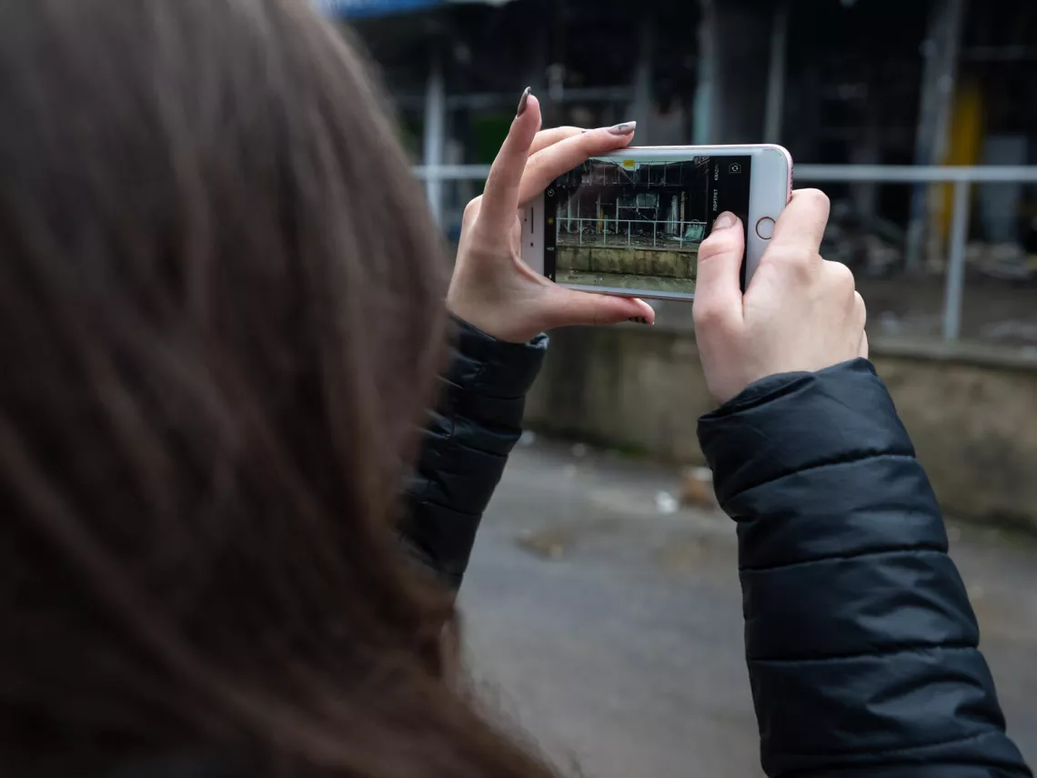 Nika (11) is taking picture next to a destroyed building in Kharkiv, Ukraine. Her favourite shop used to be here.