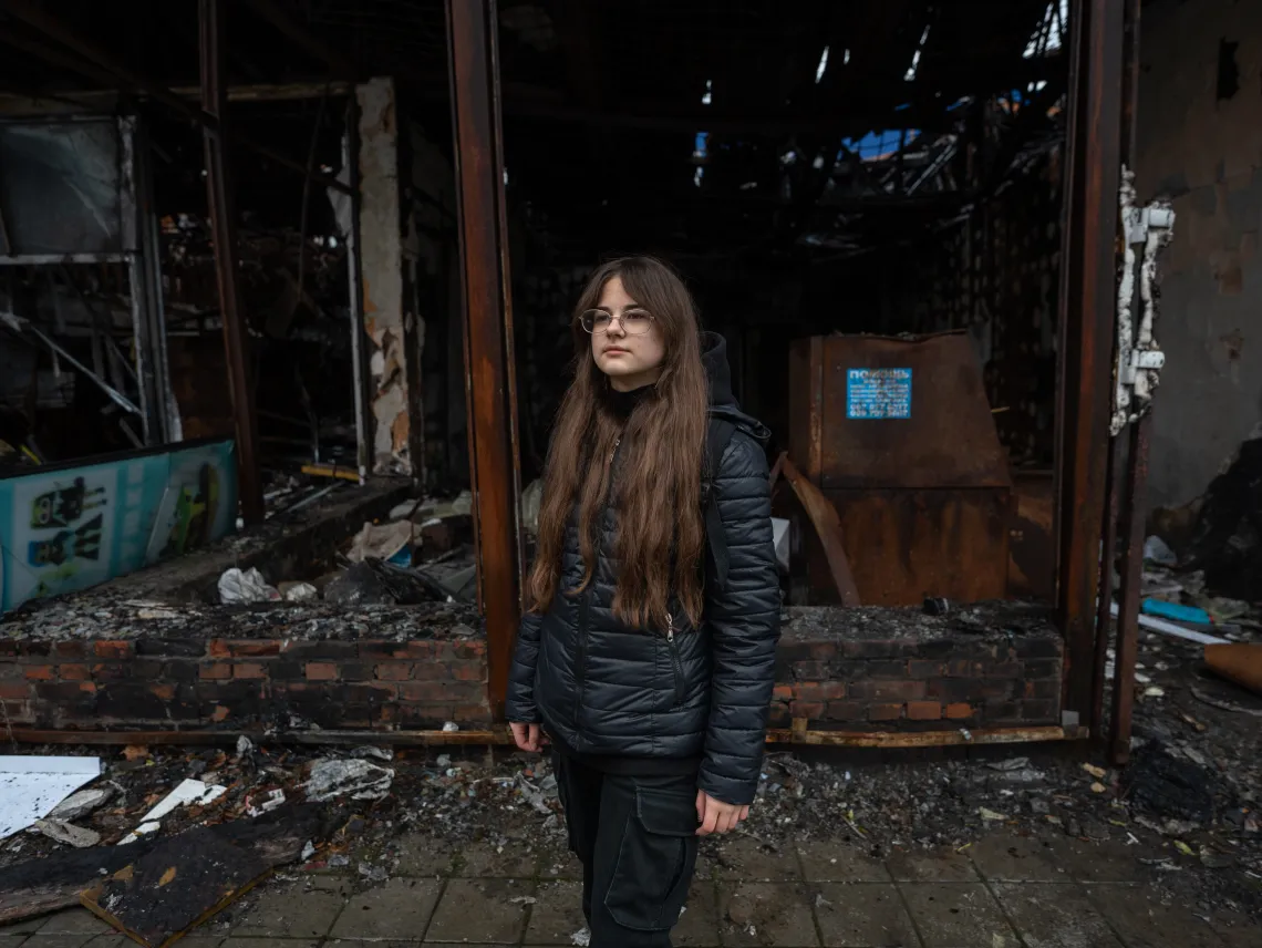 Nika (11) is taking picture next to a destroyed building in Kharkiv, Ukraine. Her favourite shop used to be here.
