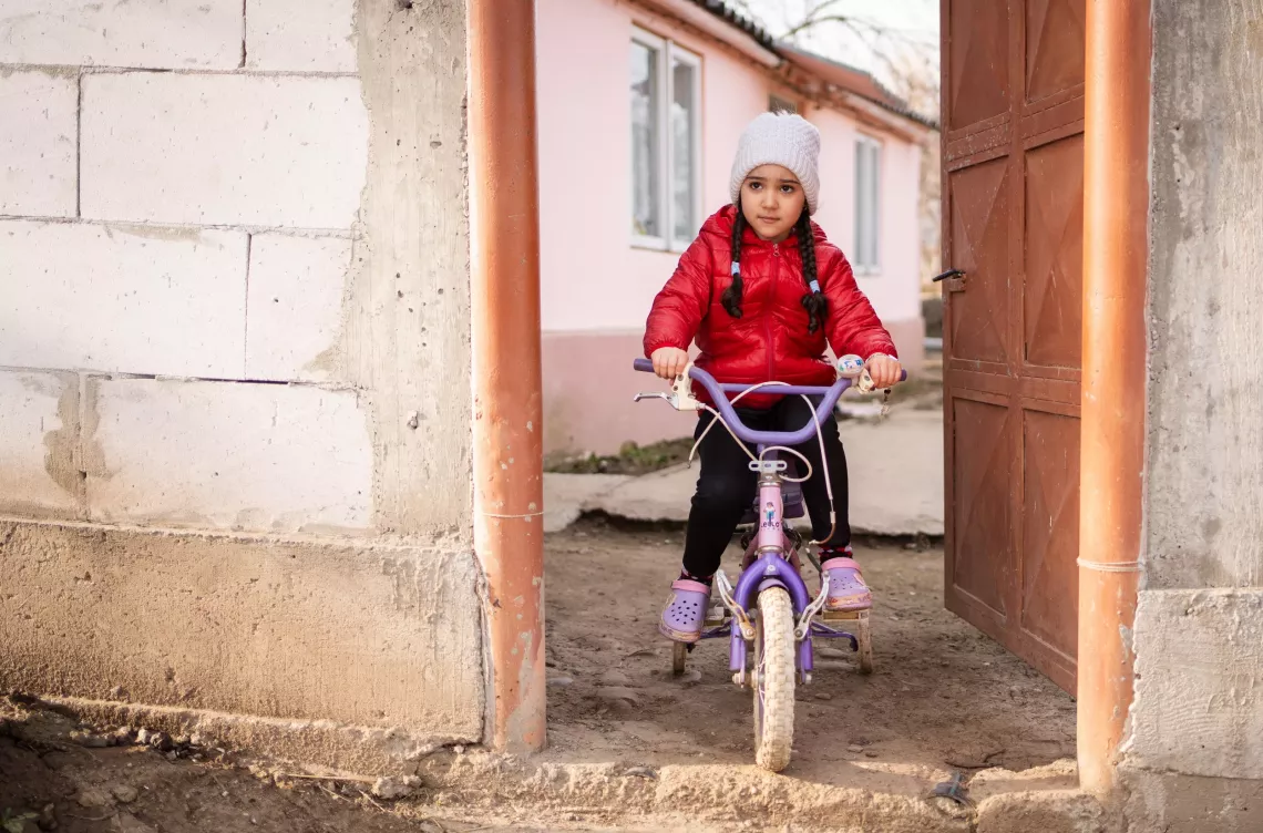 Five-year-old Antonia cycles in the dusty yard of her home in Scărișoara, Romania, in February 2024. After being hospitalized with pneumonia at age two, she must be careful about how much contact she has with other children, since even a minor cold can cause further health complications. 