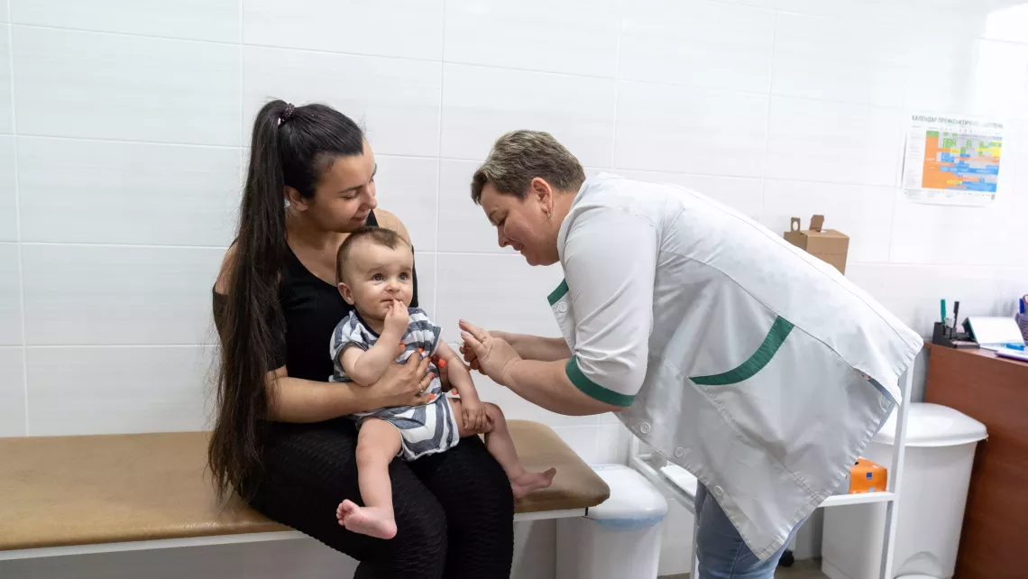 Eight-month-old Orest is in his mother's hands, waiting for vaccination next to the nurse Tetiana, at the health centre in Kyiv's Shevchenkivskyi district.