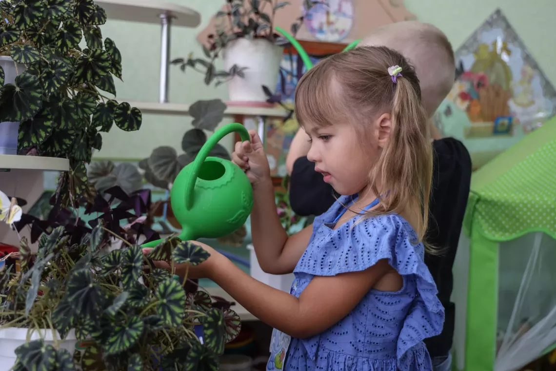 Bringing the outdoors in, such as with plants, can be one way to connect children with nature even without green space &ndash; as with this little girl in a kindergarten in Liubar,  Ukraine in August 2024. 