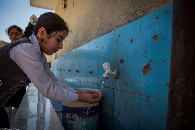 A girl washes her face at a school rehabilitated by UNICEF in Iraq.