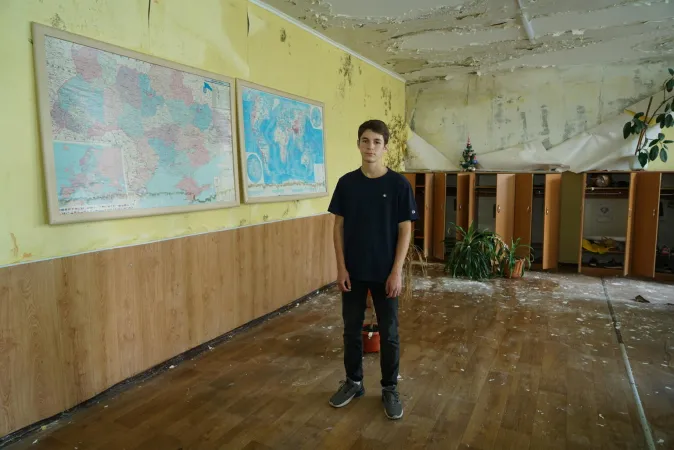 Boy stands amongst the ruins of his school in Ukraine.