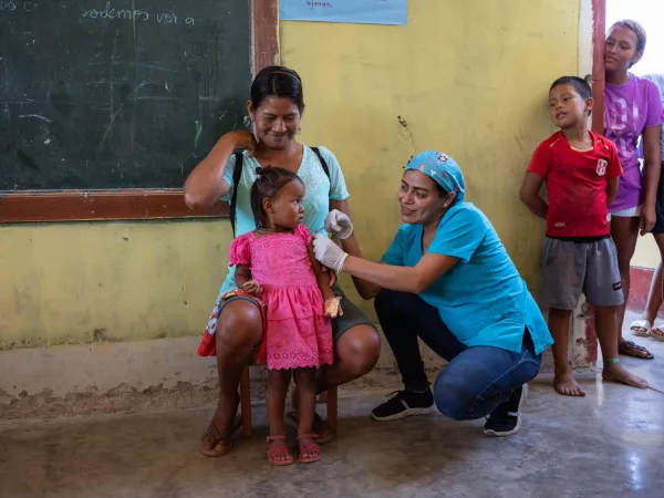 In Peru, 2-year-old Marta is held by her mother while receiving her influenza vaccine.