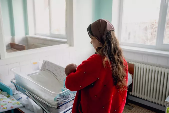 Svetlana holds her baby and looks at him. 