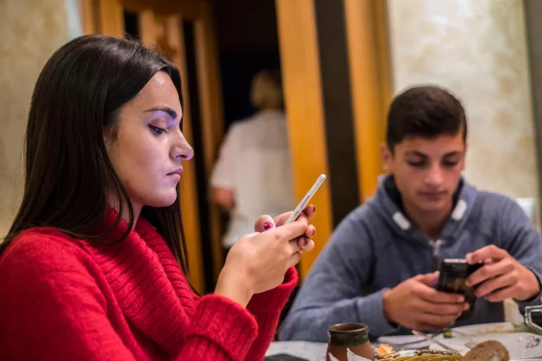  Gabriela, 17, and her brother Mihai, 14, use their phones at the dinner table in Moldova.