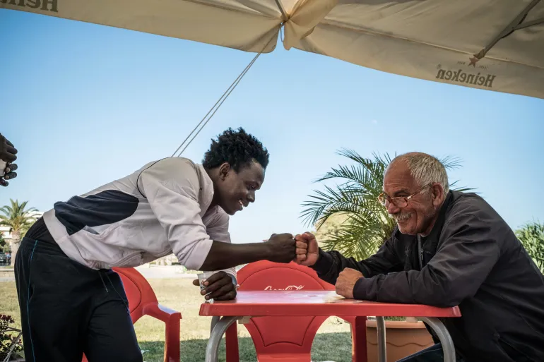 Mohammad, 17, bumps fists with a local Italian man near a government reception center that doubles as a lodging station for unaccompanied minors in Sicily, Italy
