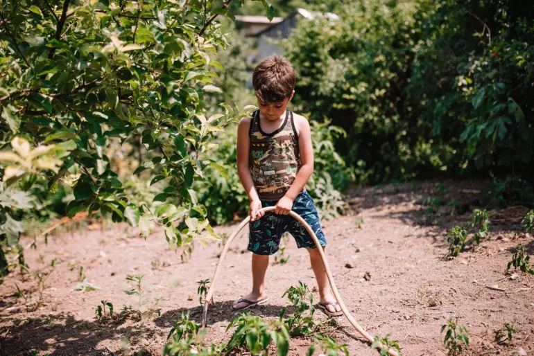 Vahe, 7, is watering the plants in their garden