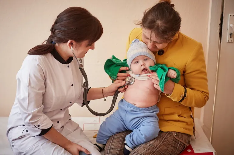A mother watches Dr. Nataliya Seredyuk checking her five-month-old baby prior to administering him immunizations at the General Practice Clinic in Bohorodchany, Ivano-Frankivsk Oblast, Ukraine.