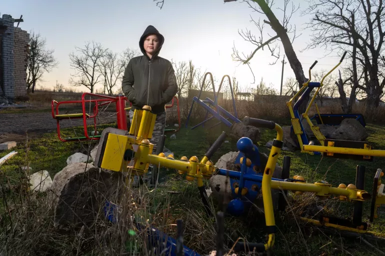 Timofii, 11 years old, stands in front of the ruins of the kindergarten he once attended in the village of Partyzanske, Mykolaiv region, destroyed by shelling.