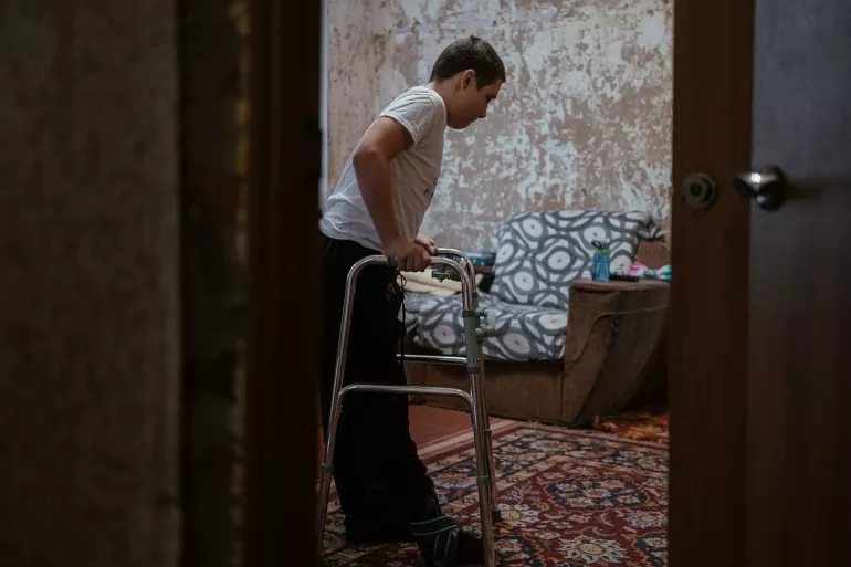 Thirteen-year-old Nazar takes careful steps with the help of a walker at home. After sustaining severe injuries from an unexploded ordnance in his village last autumn, Nazar is learning to walk again following multiple surgeries and the partial amputation of his right foot.