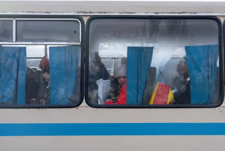 Eleven-year-old Kira sits on an evacuation bus holding her small grey dog, Kim, as she leaves Kramatorsk, Donetsk Region, Ukraine. Kira and her mother, Alona, were forced to evacuate after shelling hit a building near their home. December 2025.