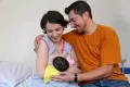 Mother is breastfeeding her new born baby while the father accompanies them.