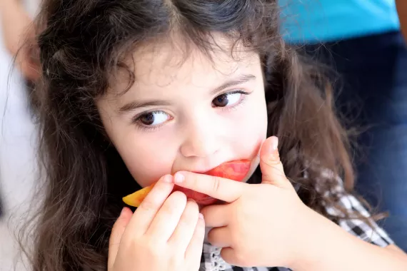 A little girl eating peach at newly opened preschool in Dovegh.