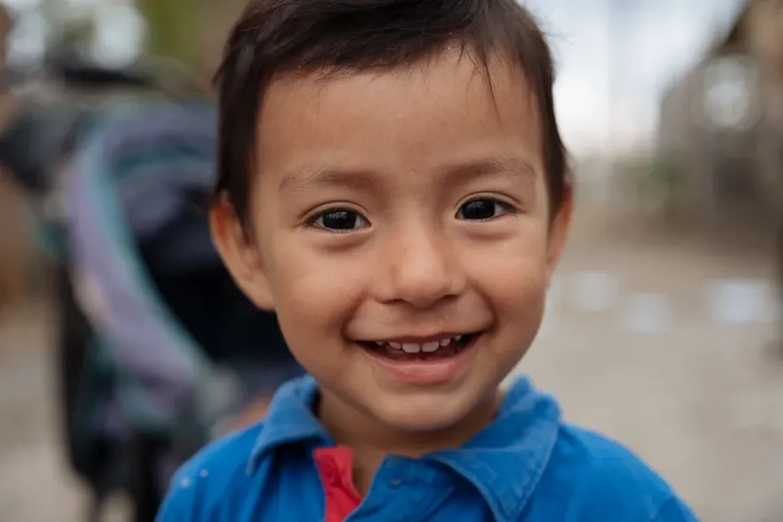Primer plano de ni&ntilde;o peque&ntilde;o sonriente con camisa azul al aire libre.