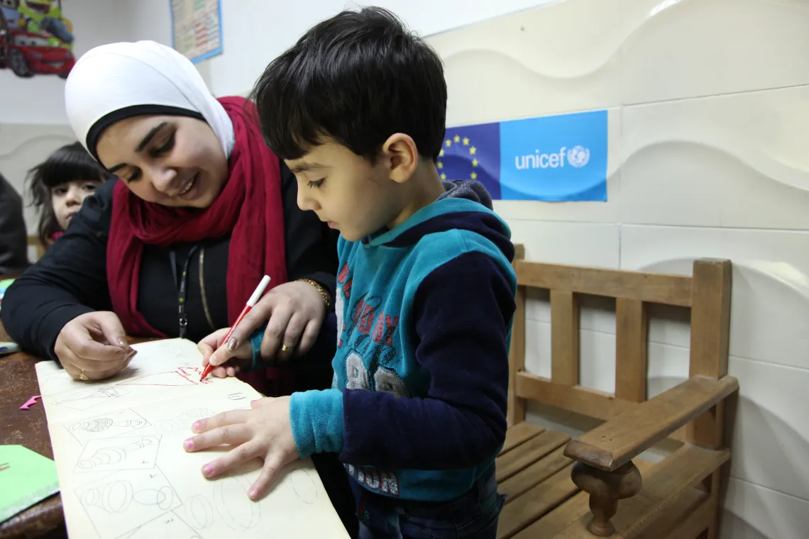 A Syrian five-year-old boy engages with his teacher in arts and crafts activities, among other children from Syria and Egypt. Agyal Community School, Faisal, Alexandria. February 2017.