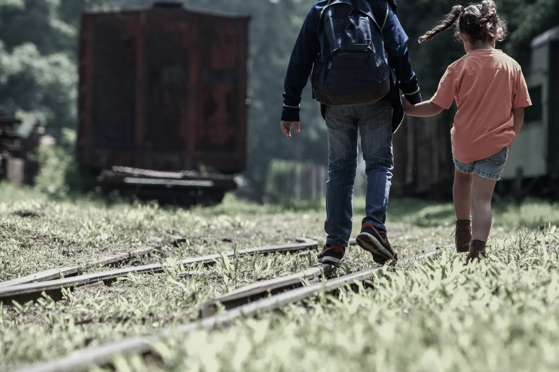 Ni&ntilde;o y ni&ntilde;a caminan en l&iacute;nea del ferrocarril