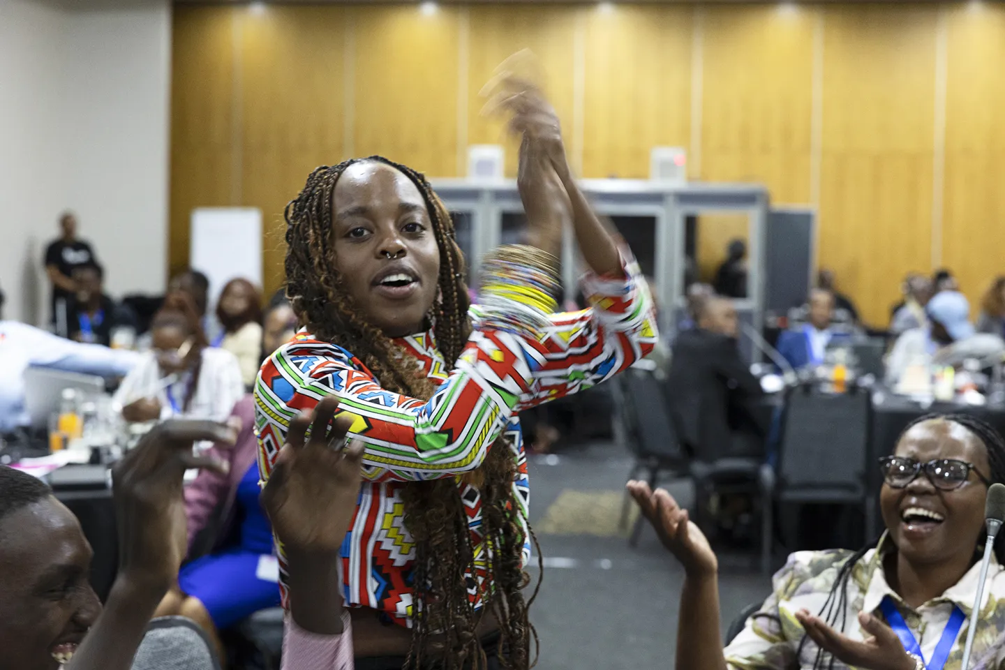 A woman claps her hands surrounded by others in a conference room