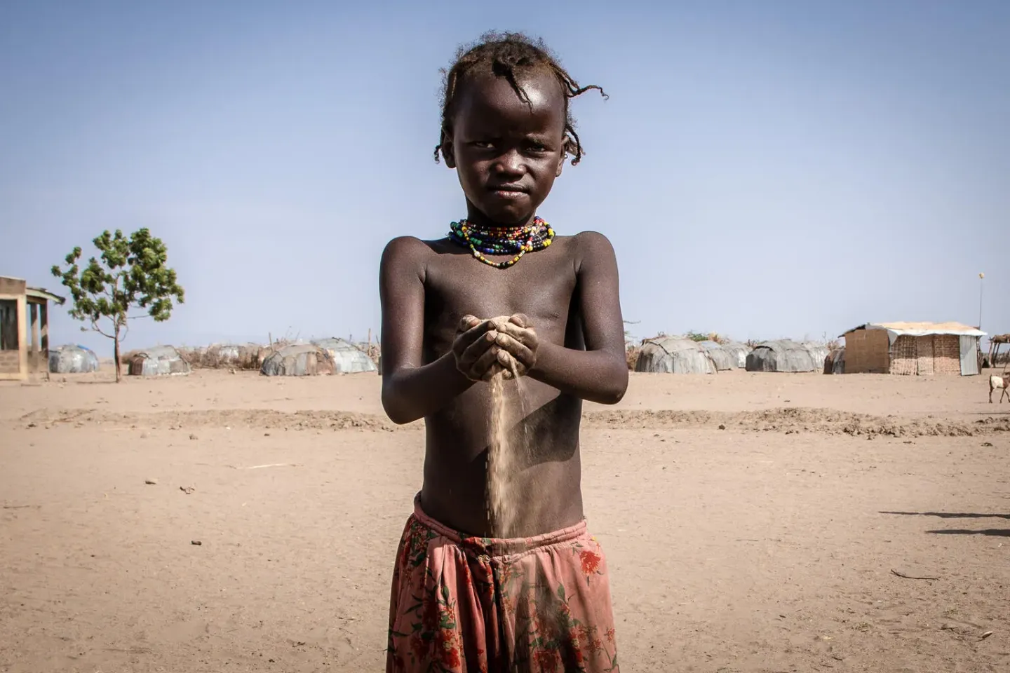 Sand flows from a child's hand like through an hourglass. 