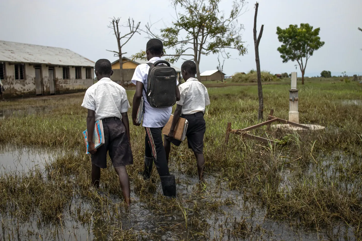 Students walk through stagnant floodwater on their way to school