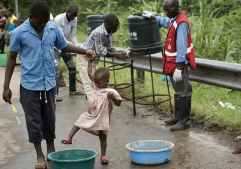 A girl washes her feet and shoes in a sanitation liquid
