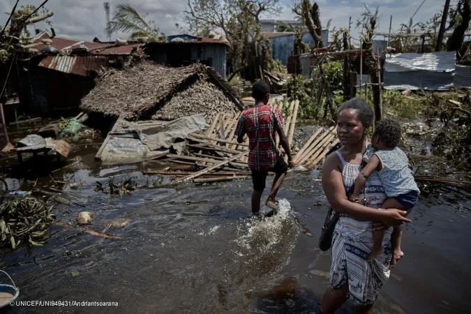 Nyekuola Riek, 30, a mother of twins, stands outside her home with floated water in the surrounding. 