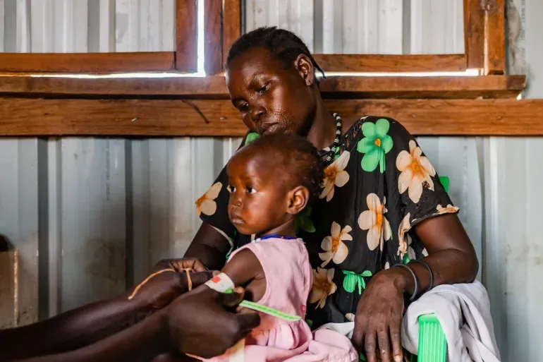 A baby, carried by her mother is checked for malnutrition at a health centre