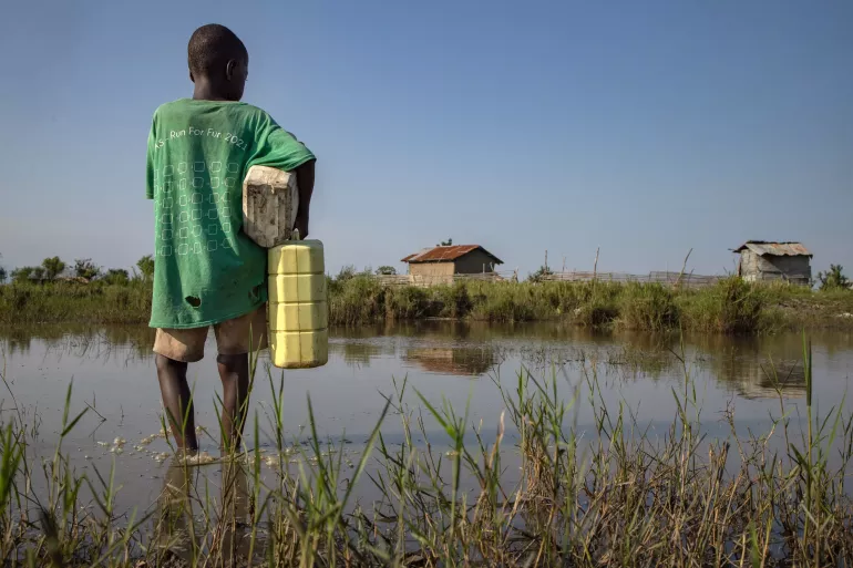 A young boy stands in the still waters from a flood in Uganda