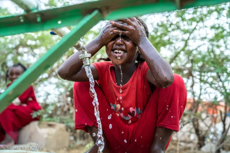 7-year-old Kaltoum washes her face at a water distribution point in Wadsharefey refugee camp in Kassala state.