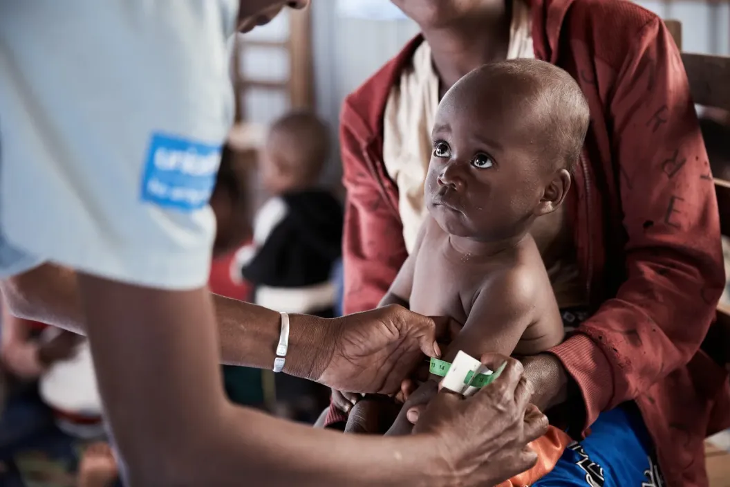 A community worker, conducts a nutrition screening by measuring a child&rsquo;s mid-upper arm circumference