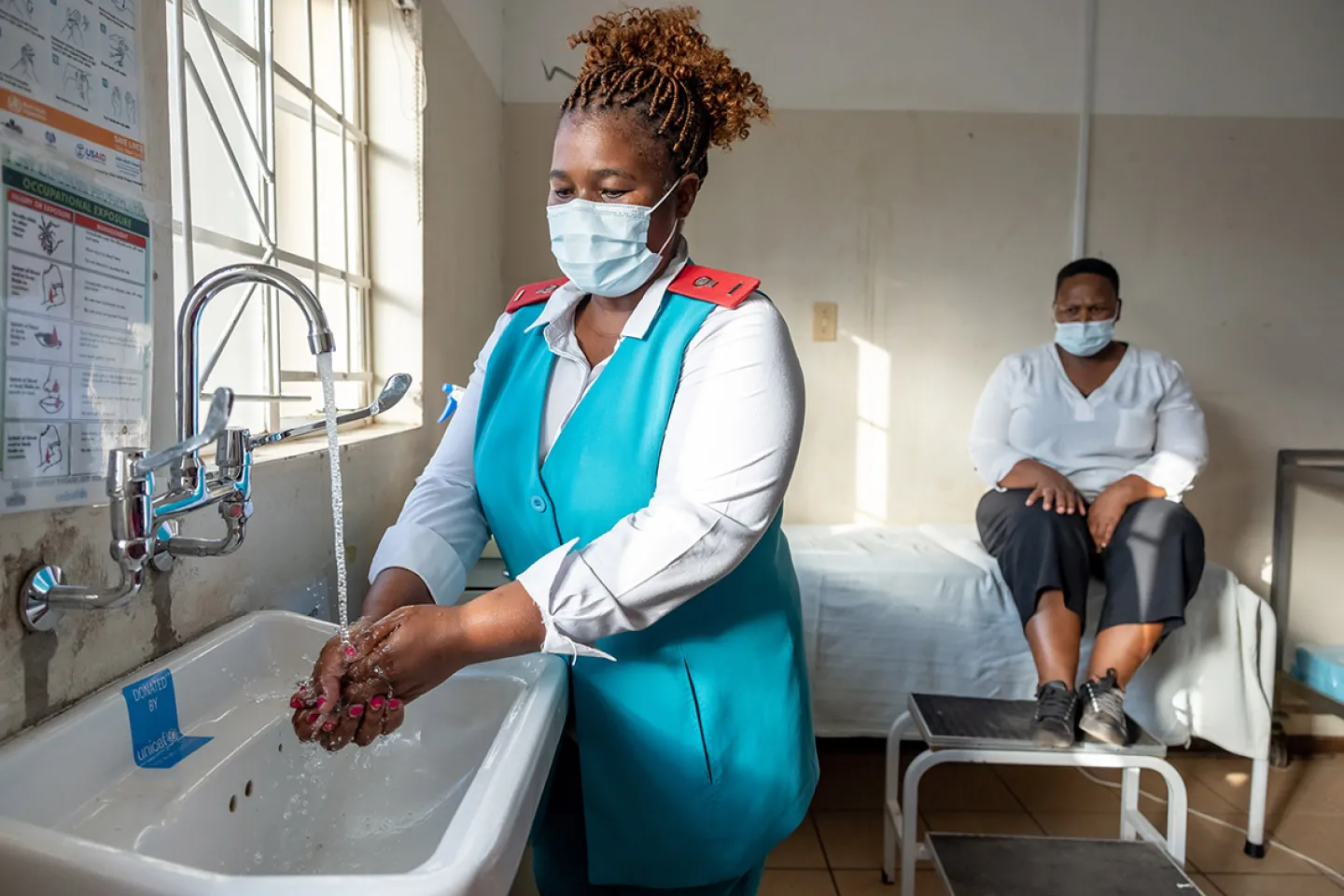 A healthcare provider washing hands before attending to a patient.