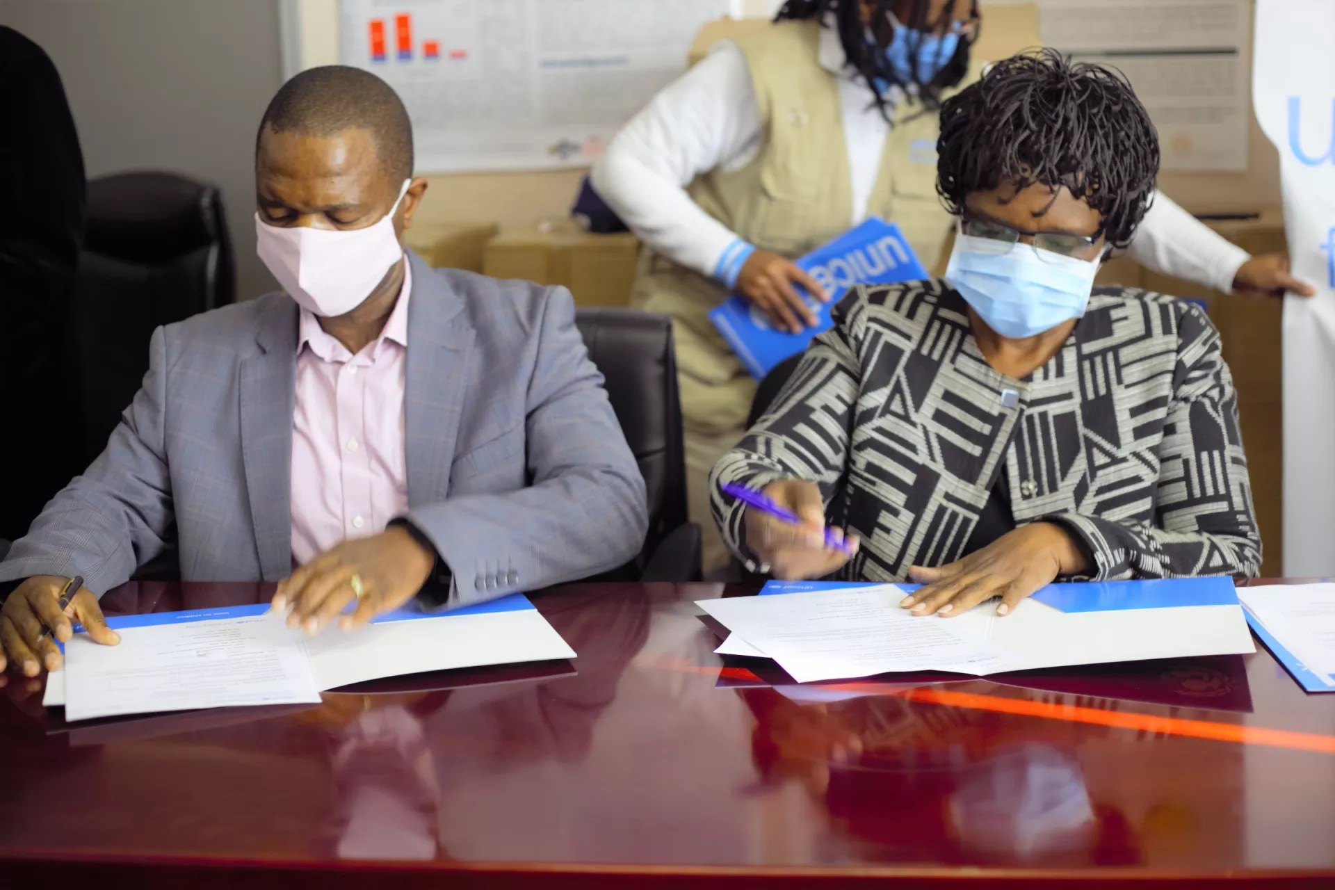 Two people sitting and writing on a table
