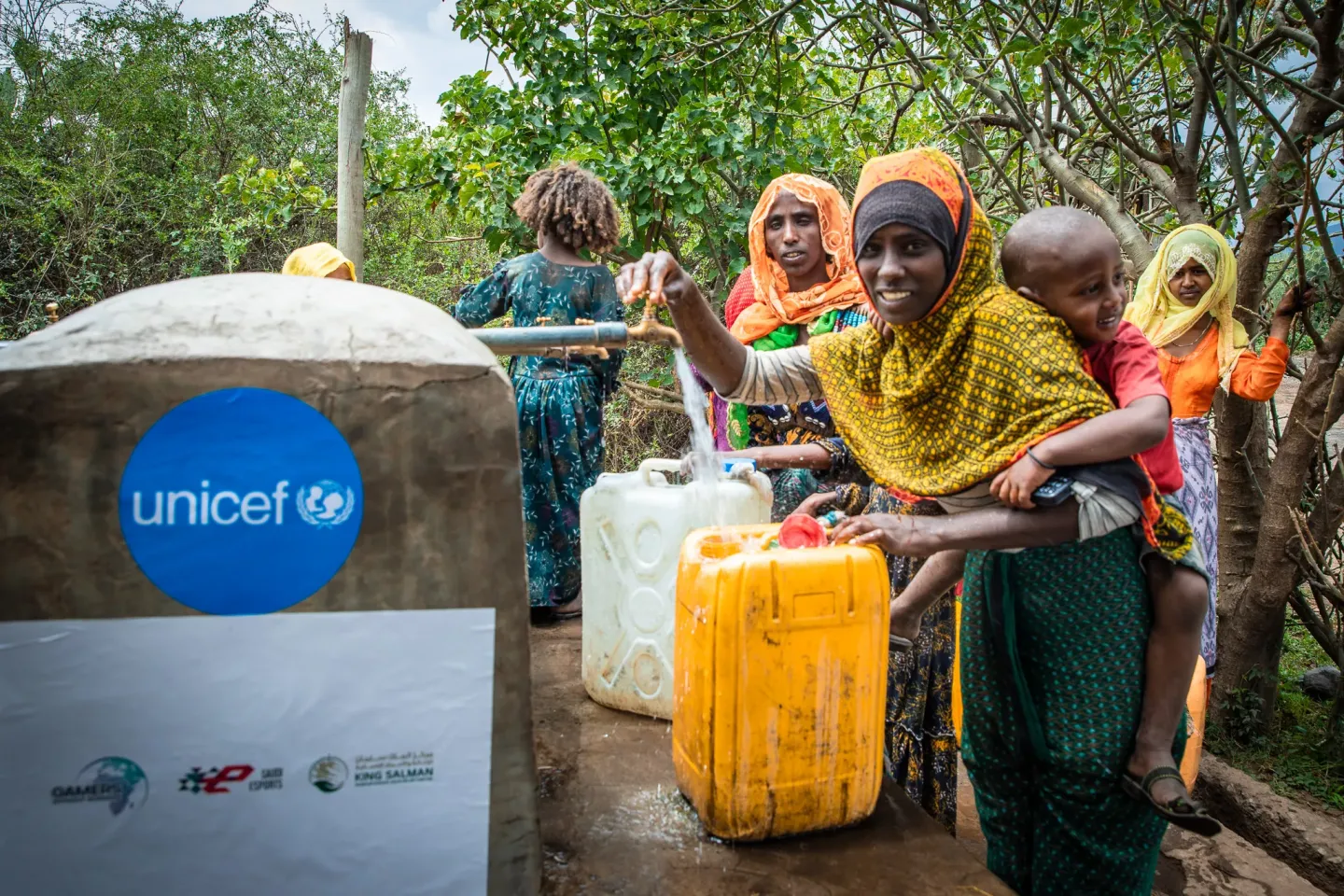 A mother holding her baby on her back and fetching water
