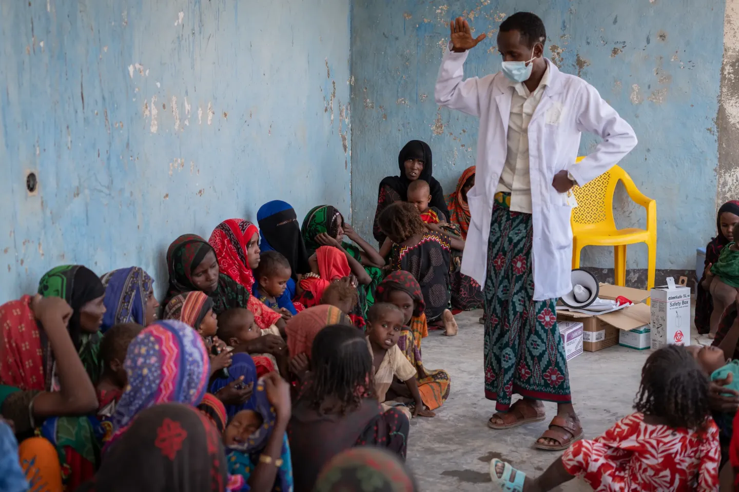 A health worker teaching mothers who are sitting in a around