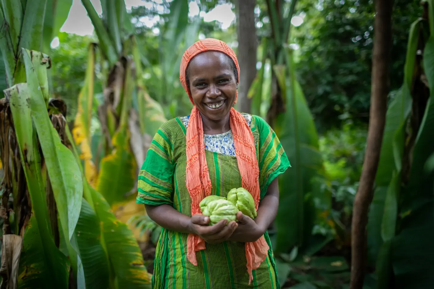 A women holds fruits in her hands and smiles to the camera
