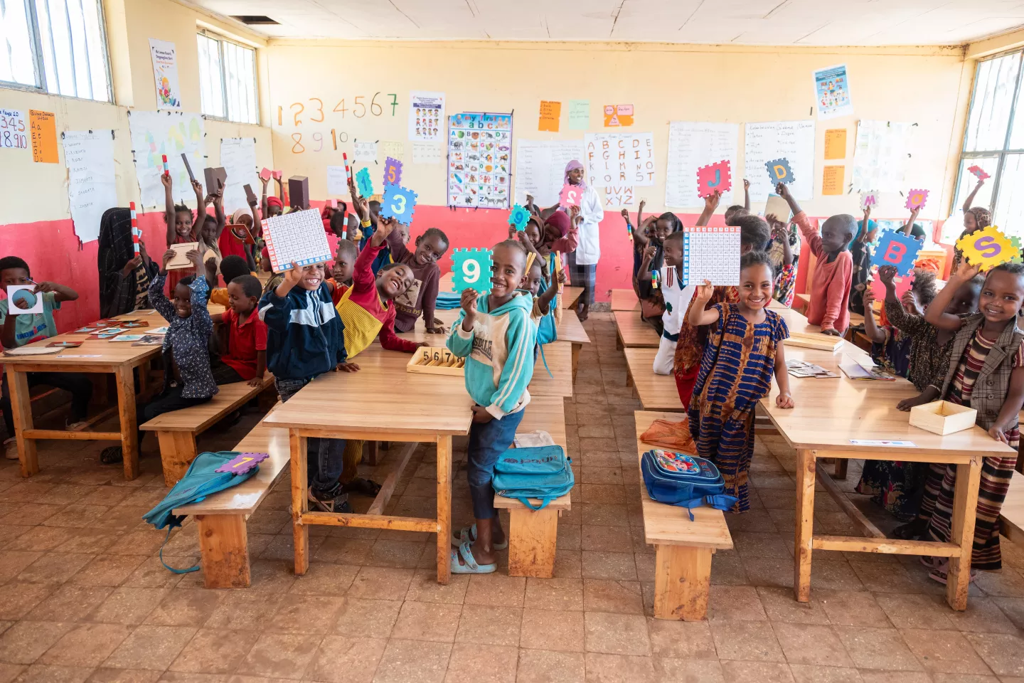 Children in class room holding play materials 