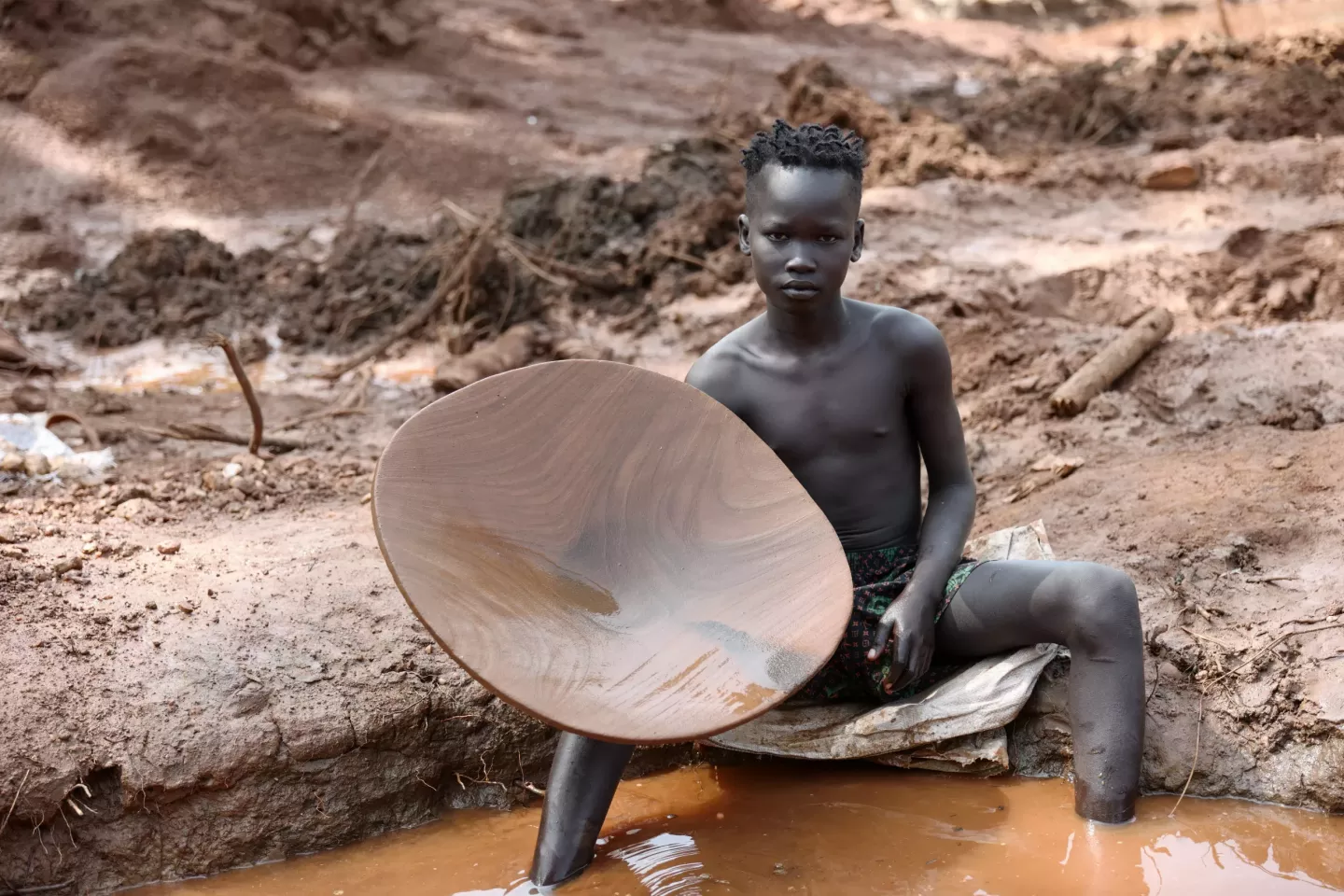 A boy holding a wooden bowl.