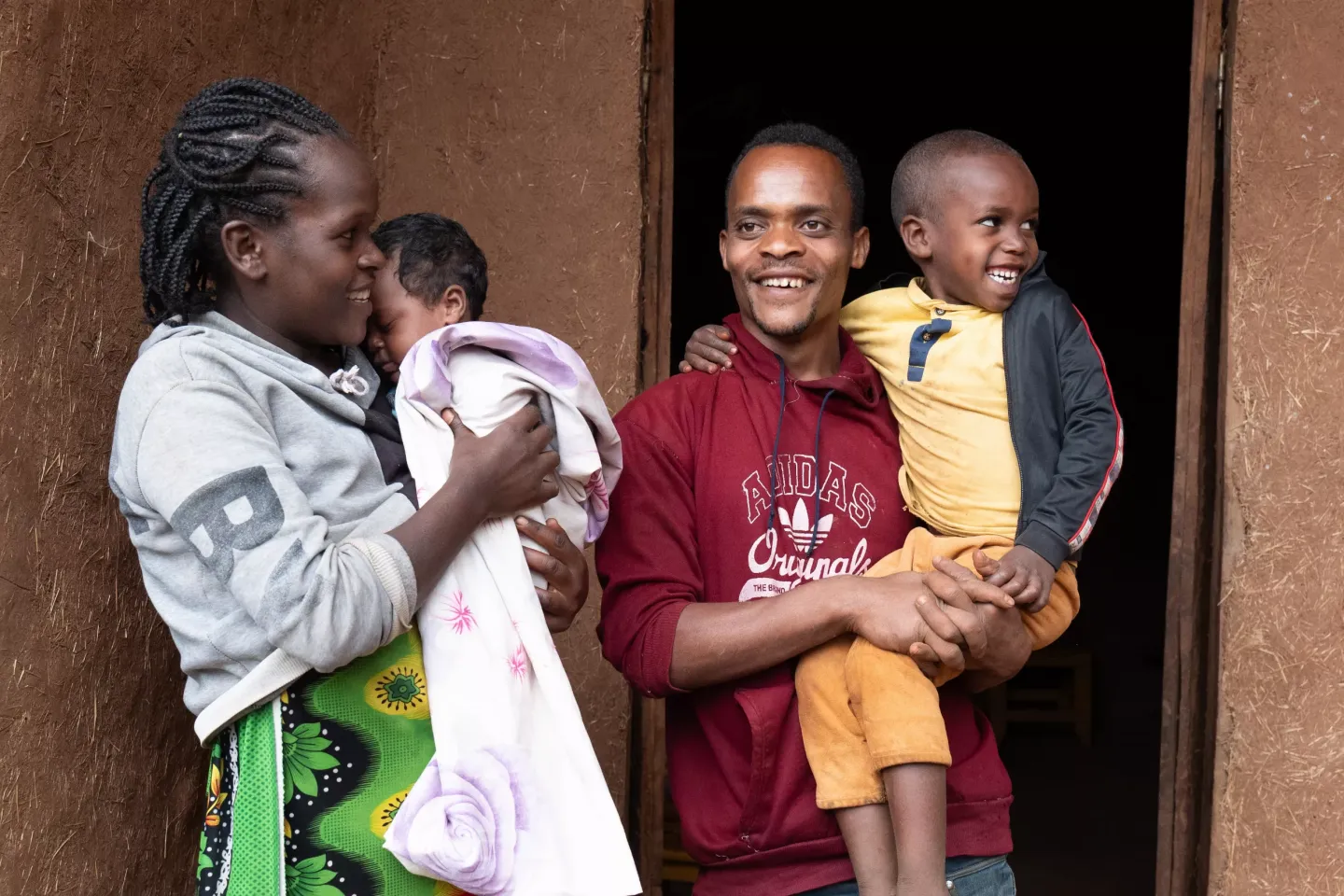 A family of four (a mother, father and two children) standing together in front of their house