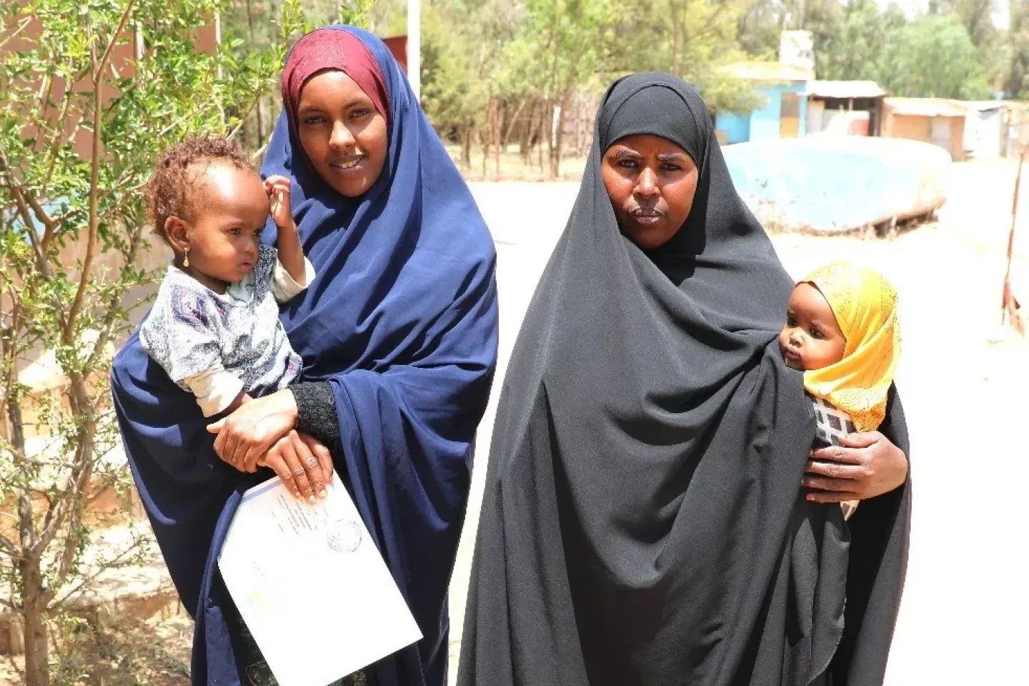 Ekram Bashir and Muna Mohammed Abdi holding thier respective children with their birthday certificate
