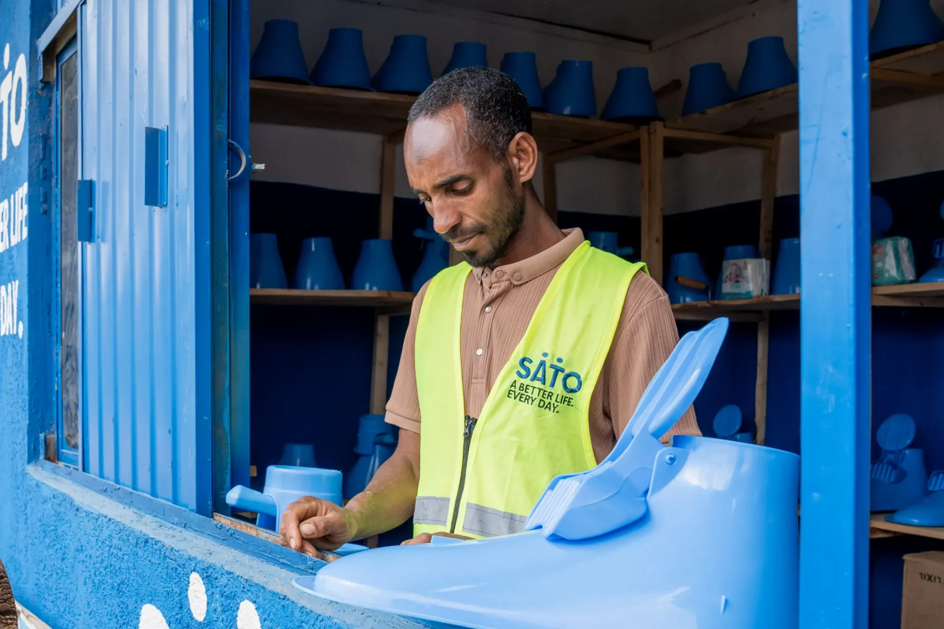 A young man standing inside his sanitary shop